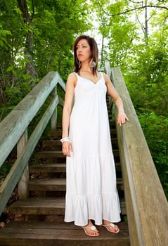 A beautiful woman standing on wooden steps in the forest.