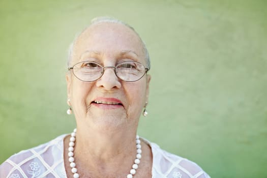 portrait of senior caucasian woman looking at camera against green wall and smiling. Horizontal shape, copy space