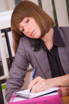 busy secretary with phone writing notice on paper