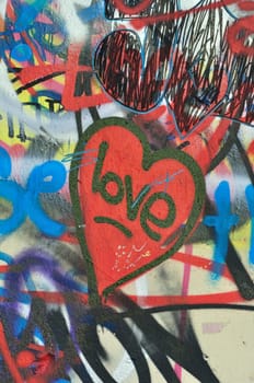 Dirty love graffiti over messy tagged urban wall background. Heart of the city.