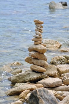 Primitive stone structure on rocky shore. Balanced rocks by the sea water.