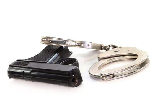 Handcuffs and gun against white background