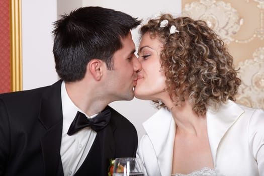 Bride and groom kissing at the wedding table