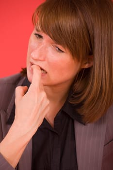 stressed woman biting her nails over red background