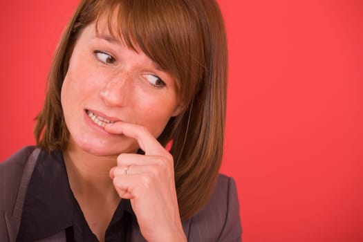 nervous businesswoman biting her nails on red background