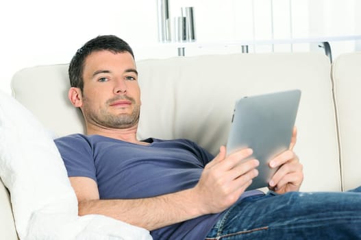 attractive relaxed and positive man is surfing on his tablet