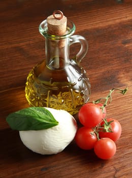 mozzarella with tomatoes, oil and basil on wood table
