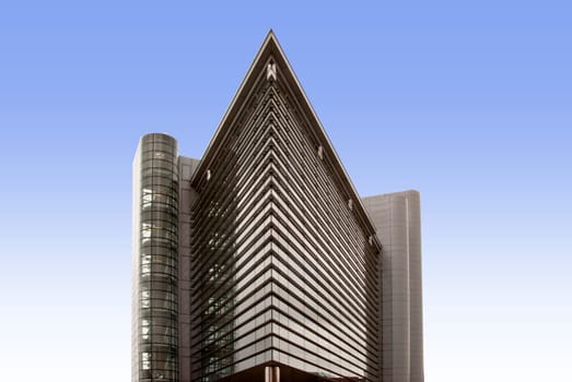 A Glass Office Block shaped like an ocean liners bows against a blue sky with reflections