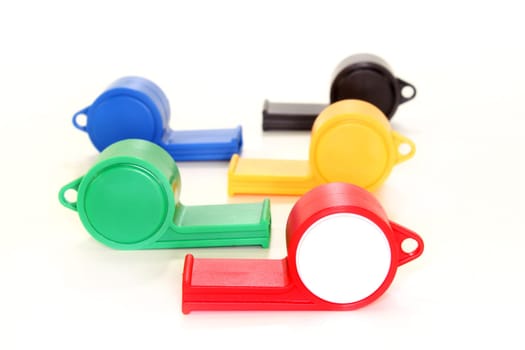 Five colorful whistles against white background