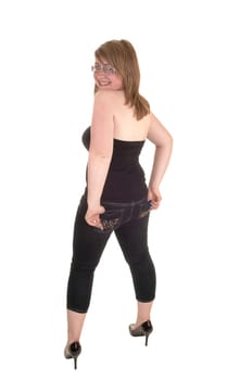 From the back, a teenager standing in the studio in jeans and high heels, looking over her shoulder, for white background.