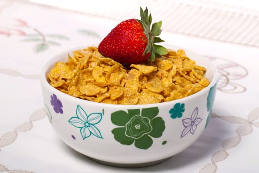 View of a bowl of cereals with strawberry on top.
