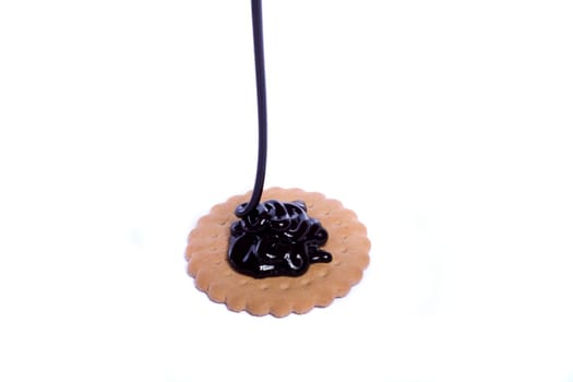 View of a round biscuit isolated on a white background with a drip of dark chocolate.