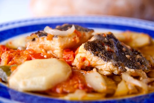 Close up view of a Portuguese meal of cod fish, potatoes and tomato.