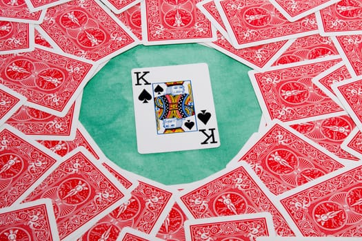 Close up view of a bunch of flipped playing cards spread on a green cloth table.