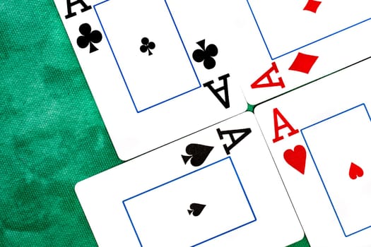 Close up view of a set of four aces spread on a green cloth table.