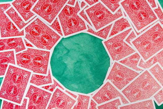 Close up view of a bunch of flipped playing cards spread on a green cloth table.