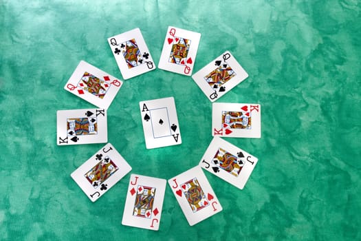 Close up view of a circle of playing cards spread on a green cloth table.