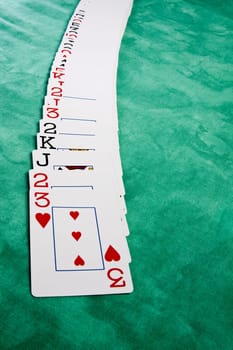Close up view of a bunch cards spread on a green cloth table.