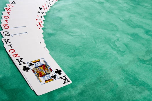 Close up view of a bunch cards spread on a green cloth table.