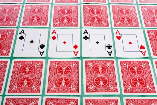 Close up view of a bunch of flipped playing cards spread on a green cloth table.