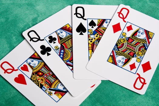 Close up view of a set of four queens spread on a green cloth table.