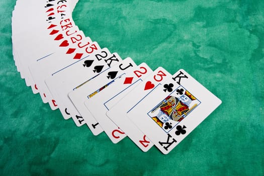 Close up view of a bunch cards spread on a green cloth table.