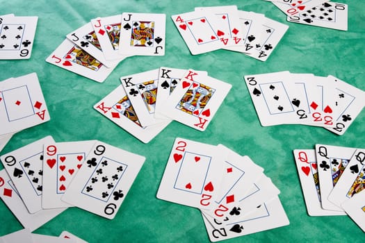 Close up view of a bunch cards spread on a green cloth table.