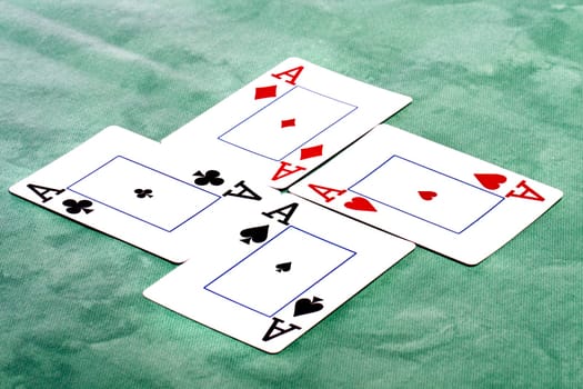Close up view of a set of four aces spread on a green cloth table.