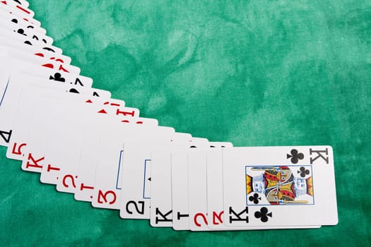Close up view of a bunch cards spread on a green cloth table.