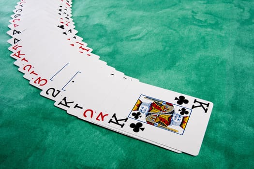 Close up view of a bunch cards spread on a green cloth table.