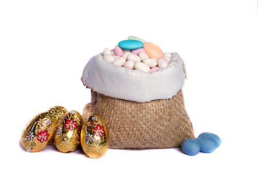 Close up view of sweet almonds and chocolate eggs inside a sack isolated on a white background.