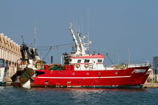View of a red fishing boat anchored on the docks.