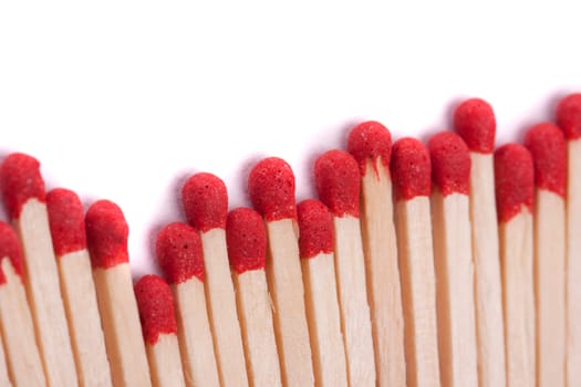 Close up view of a bunch of matches with red heads on a white background.