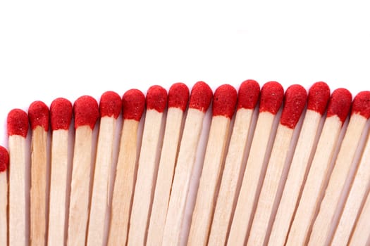 Close up view of a bunch of matches with red heads on a white background.