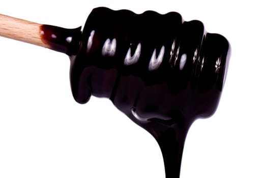 Close up view of a honey dipper with dark chocolate isolated on a white background.