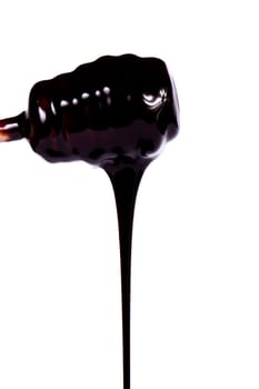 Close up view of a honey dipper with dark chocolate isolated on a white background.