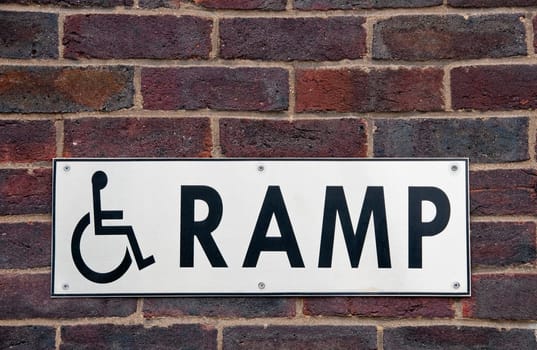 Wheelchair ramp sign on a brick wall