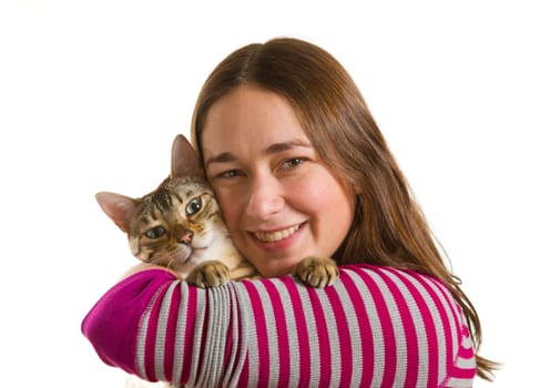 Bengal cat sits on shoulder of young woman and stares at camera in isolated studio shot showing love between pet and owner