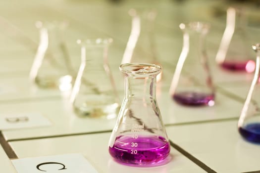 Close view detail of several chemistry beakers on a table.
