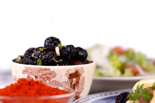 Close up view of a some tempered dry black olives and a salad.