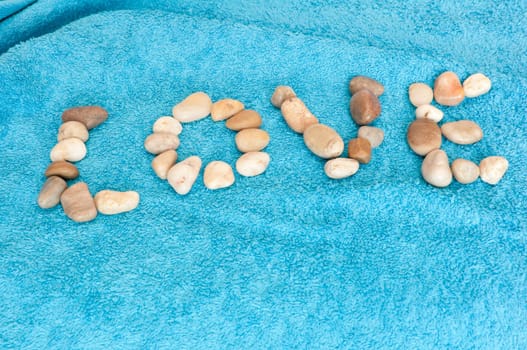 Love Sign Made of Pebbles on Blue Towel
