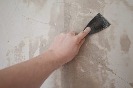 The cracks of a wall are filled with a spatula.