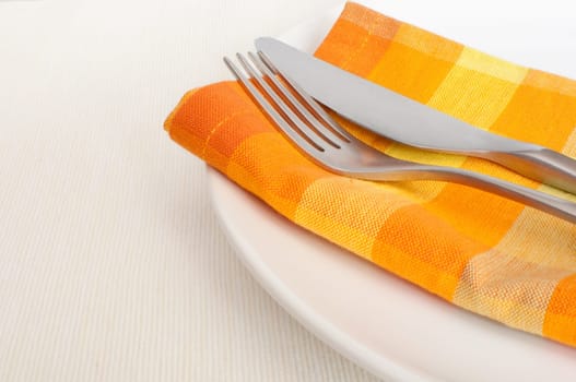Plate, Cutlery and Orange Napkin on Tablecloth in Restaurant