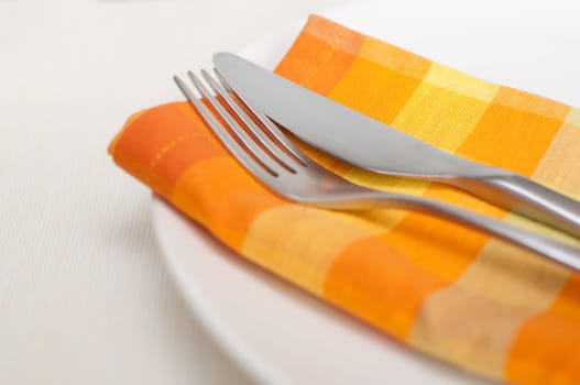 Plate, Cutlery and Orange Napkin on Tablecloth in Restaurant - Shallow Depth of Field