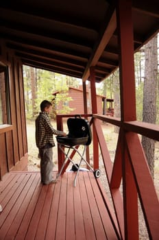 Boy on porch cleaning a barbecue