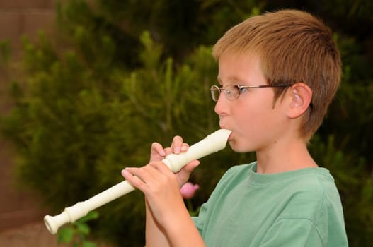 Young boy playing a recorder musical instrument