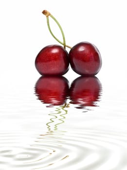 Fresh cherries on a white background and reflected on water.