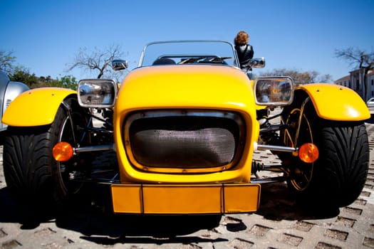 Close view of a weird yellow sports car parked on a park.