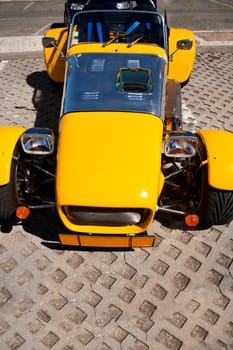 Close view of a weird yellow sports car parked on a park.