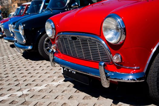 View of several mini classic cars aligned on a row.